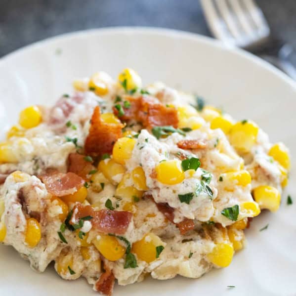 Plate with creamy corn and bacon, topped with extra bacon.