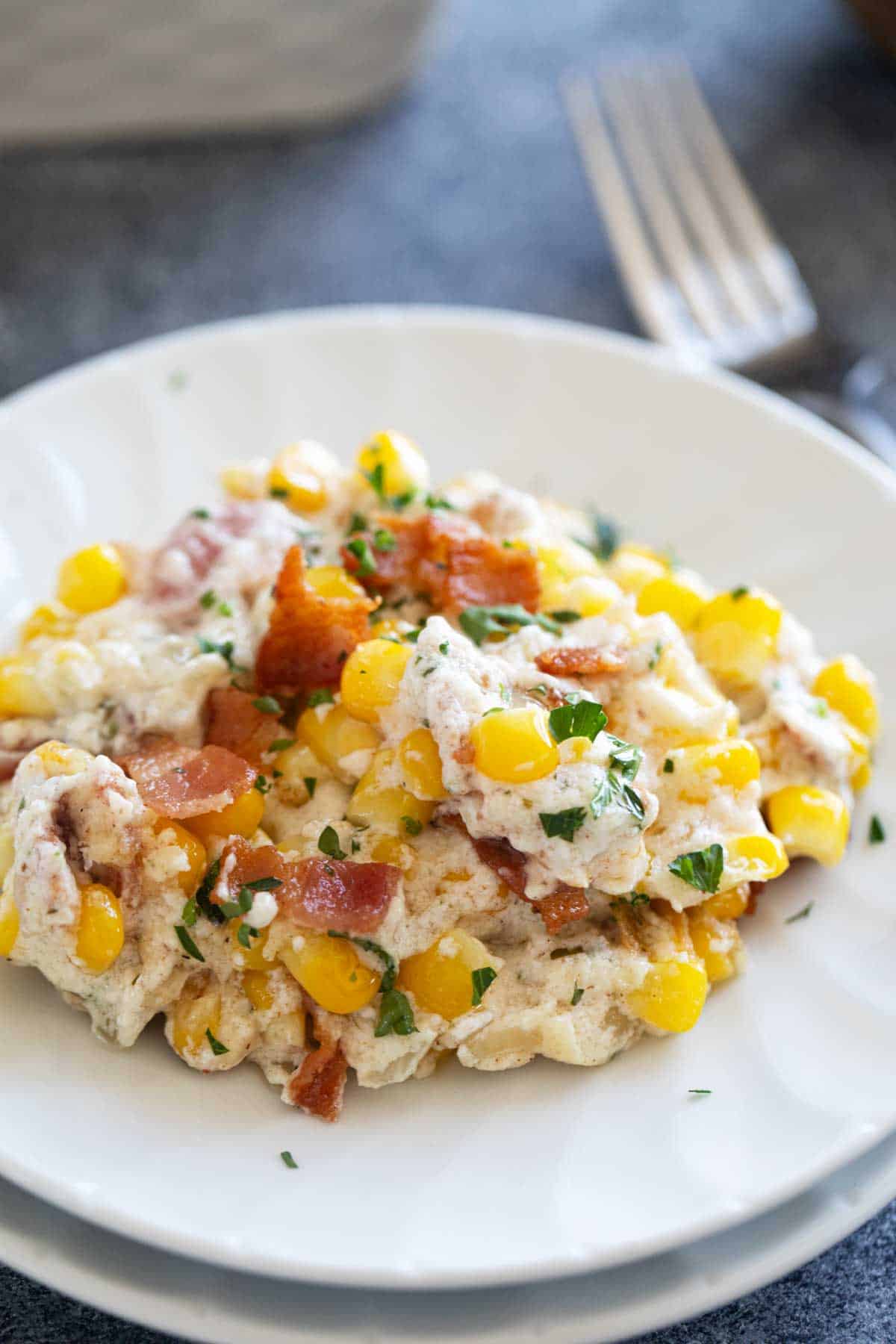 Plate with creamy corn and bacon, topped with extra bacon.