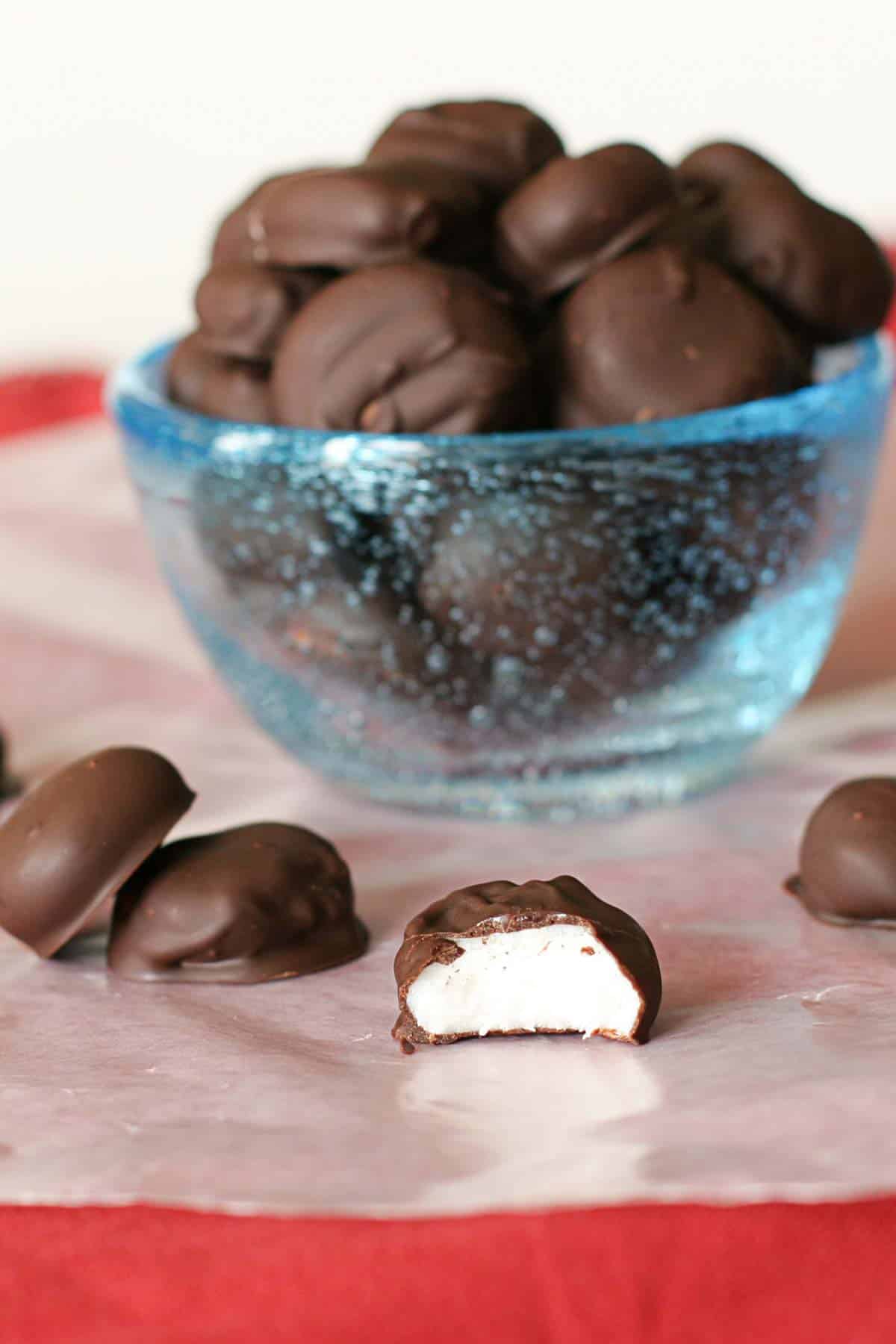 Bowl of homemade junior mints, with one mint on the side with a bite taken from it.