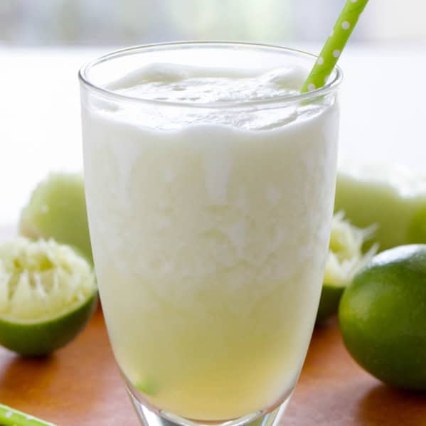 Honeydew Lime Smoothie with limes in the background.