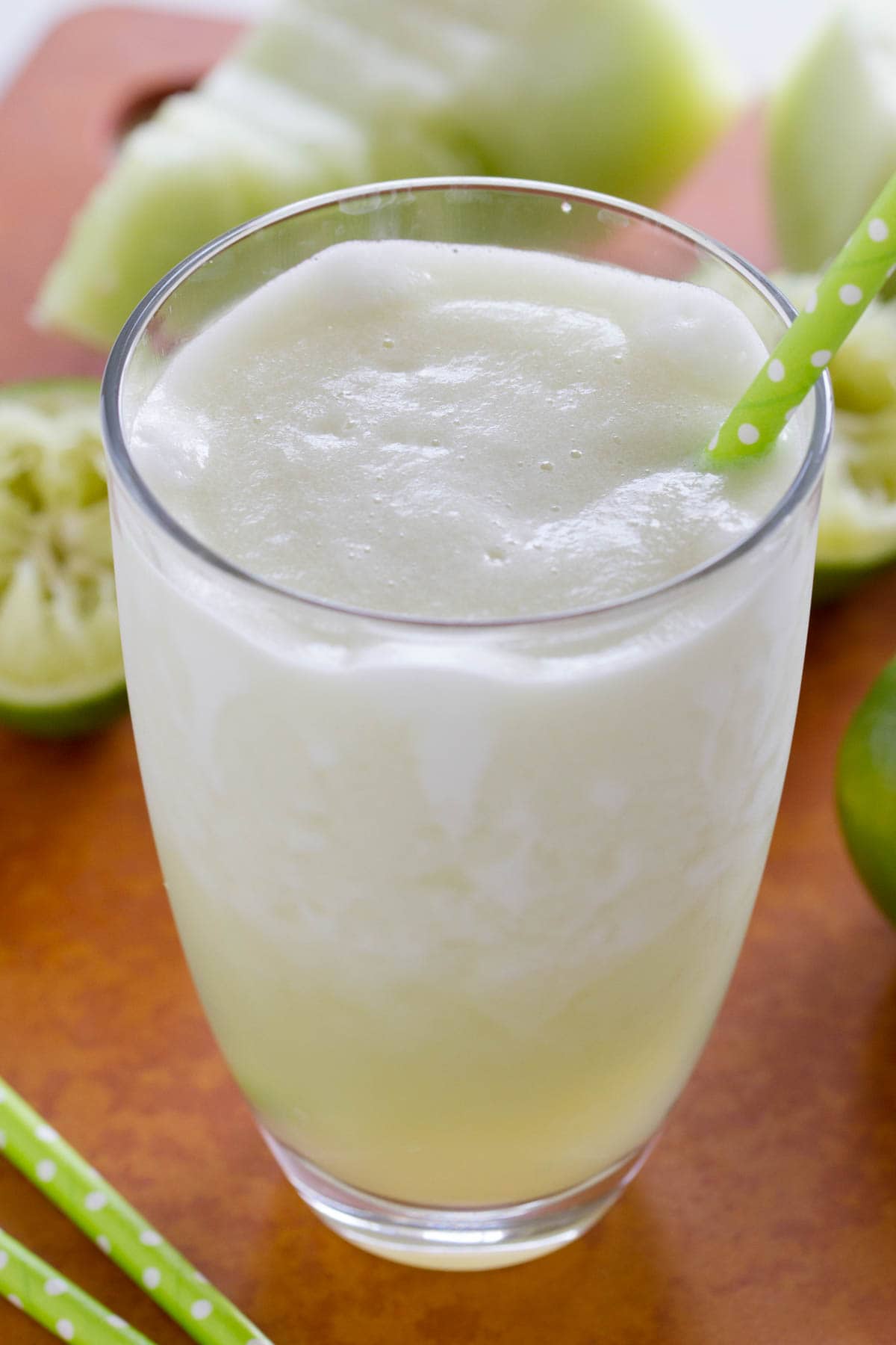 Honeydew Lime Smoothie in a glass with green straws.