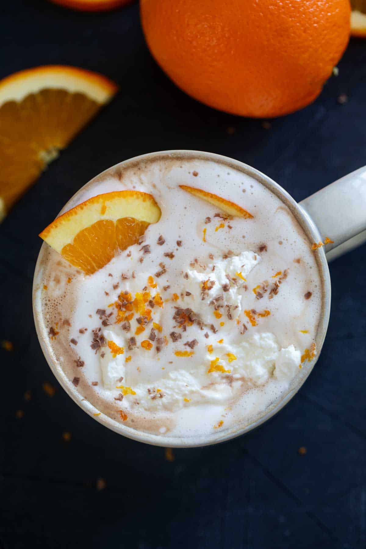 Orange hot chocolate topped with whipped cream and an orange slice.