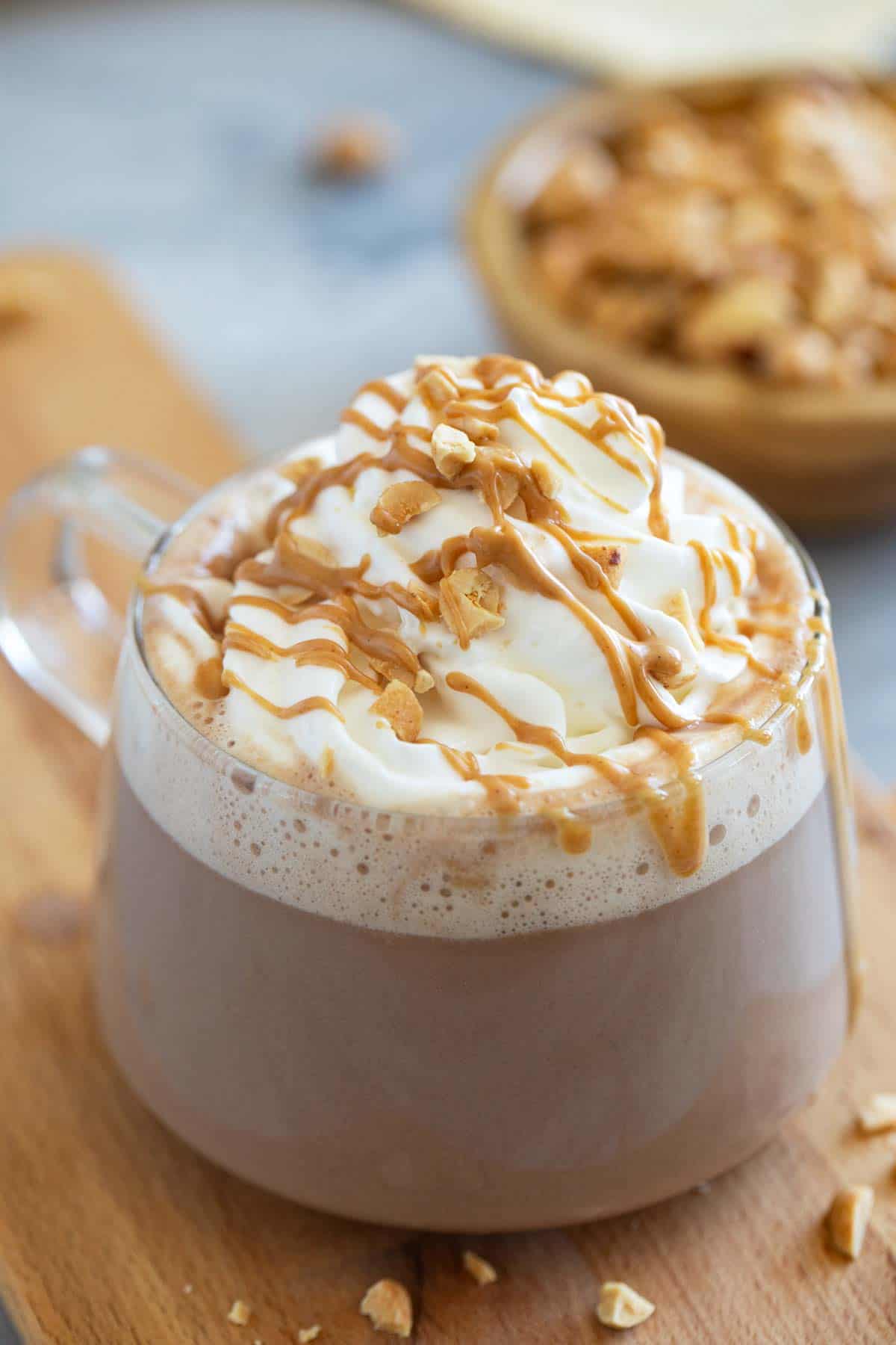 Glass mug with peanut butter hot chocolate, topped with whipped cream.