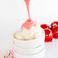 Drizzling peppermint marshmallow sauce over a scoop of vanilla ice cream.