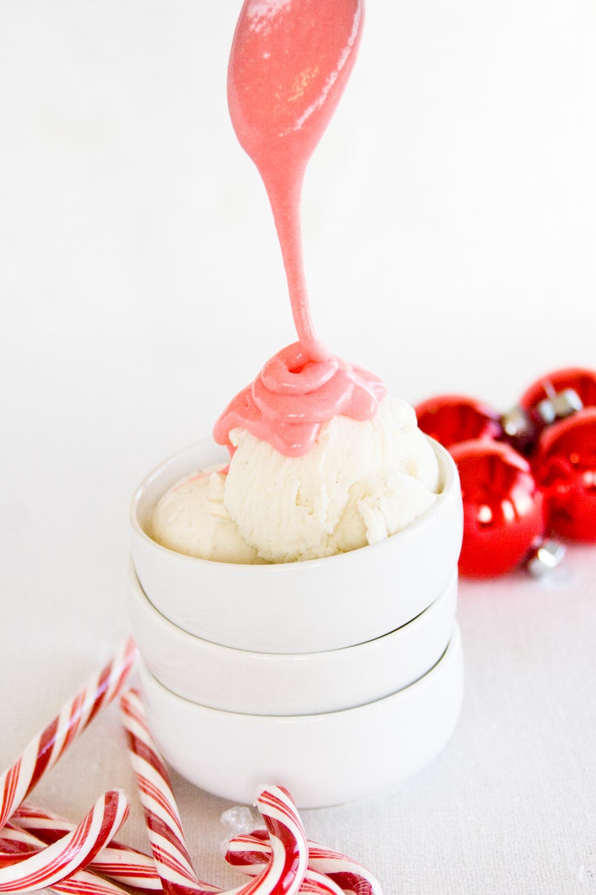 Drizzling peppermint marshmallow sauce over a scoop of vanilla ice cream.