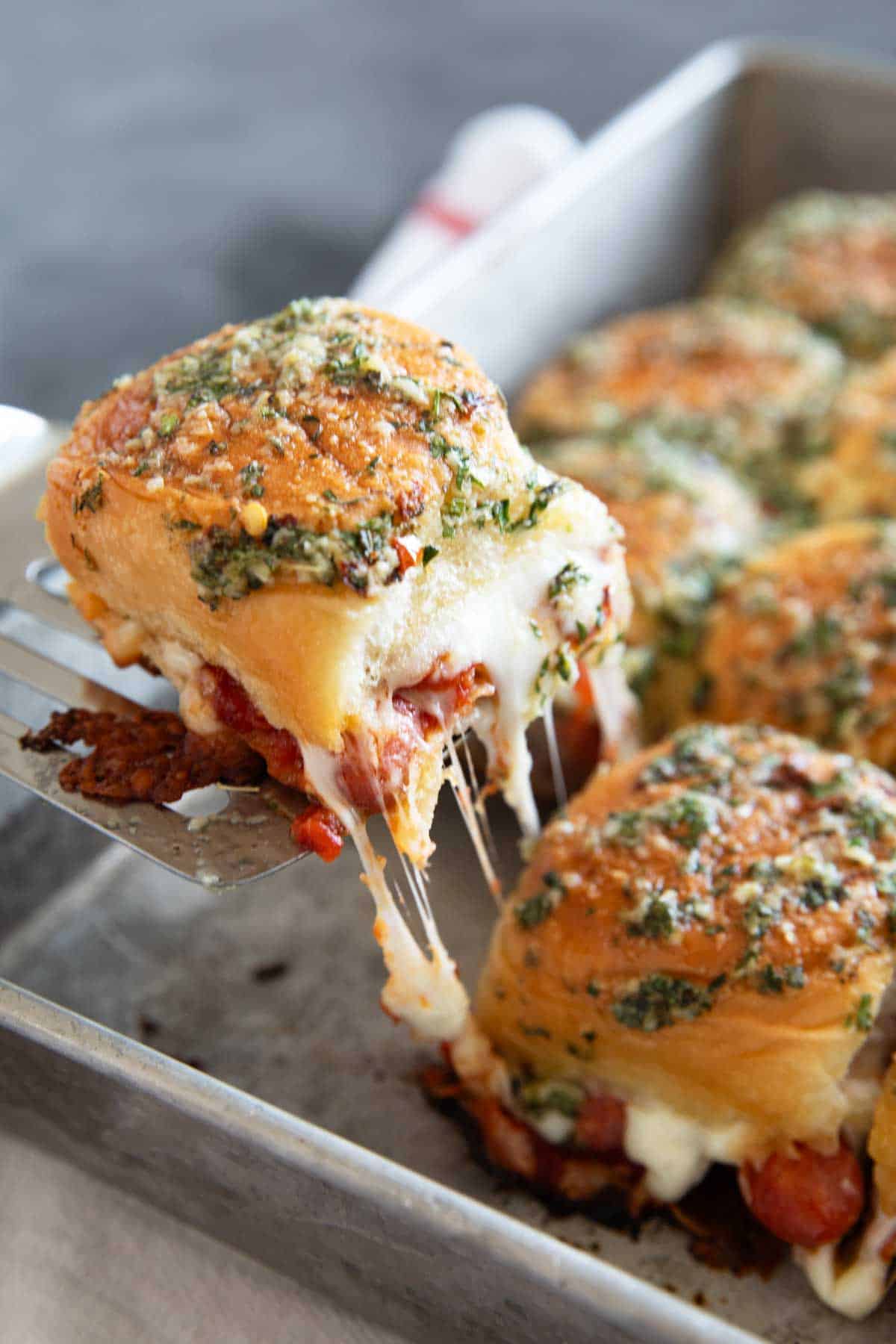 Pulling a pepperoni pizza slider for the baking pan.