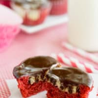 Red Velvet Cheesecake Cupcake cut in half to show cheesecake and chocolate chip center.