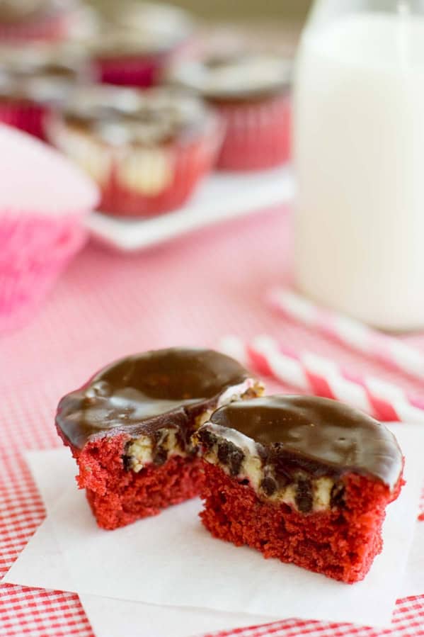 Red Velvet Cheesecake Cupcake cut in half to show cheesecake and chocolate chip center.