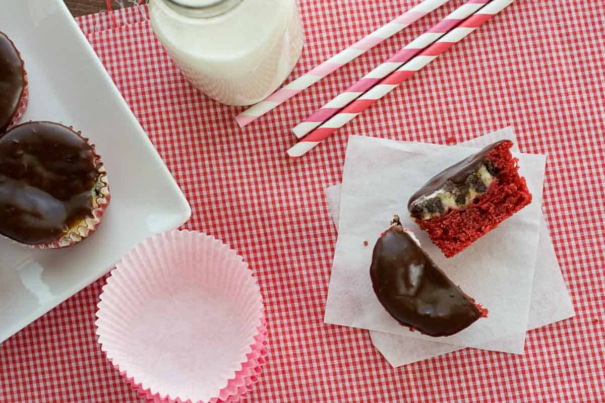 A red velvet cheesecake cupcake cut in half, with more on the side.