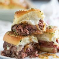 Three roast beef sliders, with one stacked on top of the others.