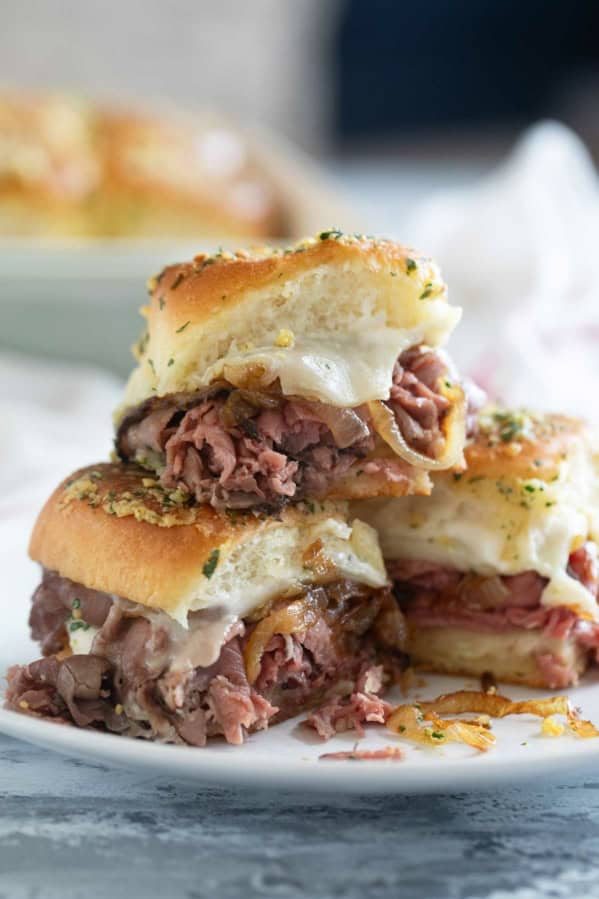 Three roast beef sliders, with one stacked on top of the others.