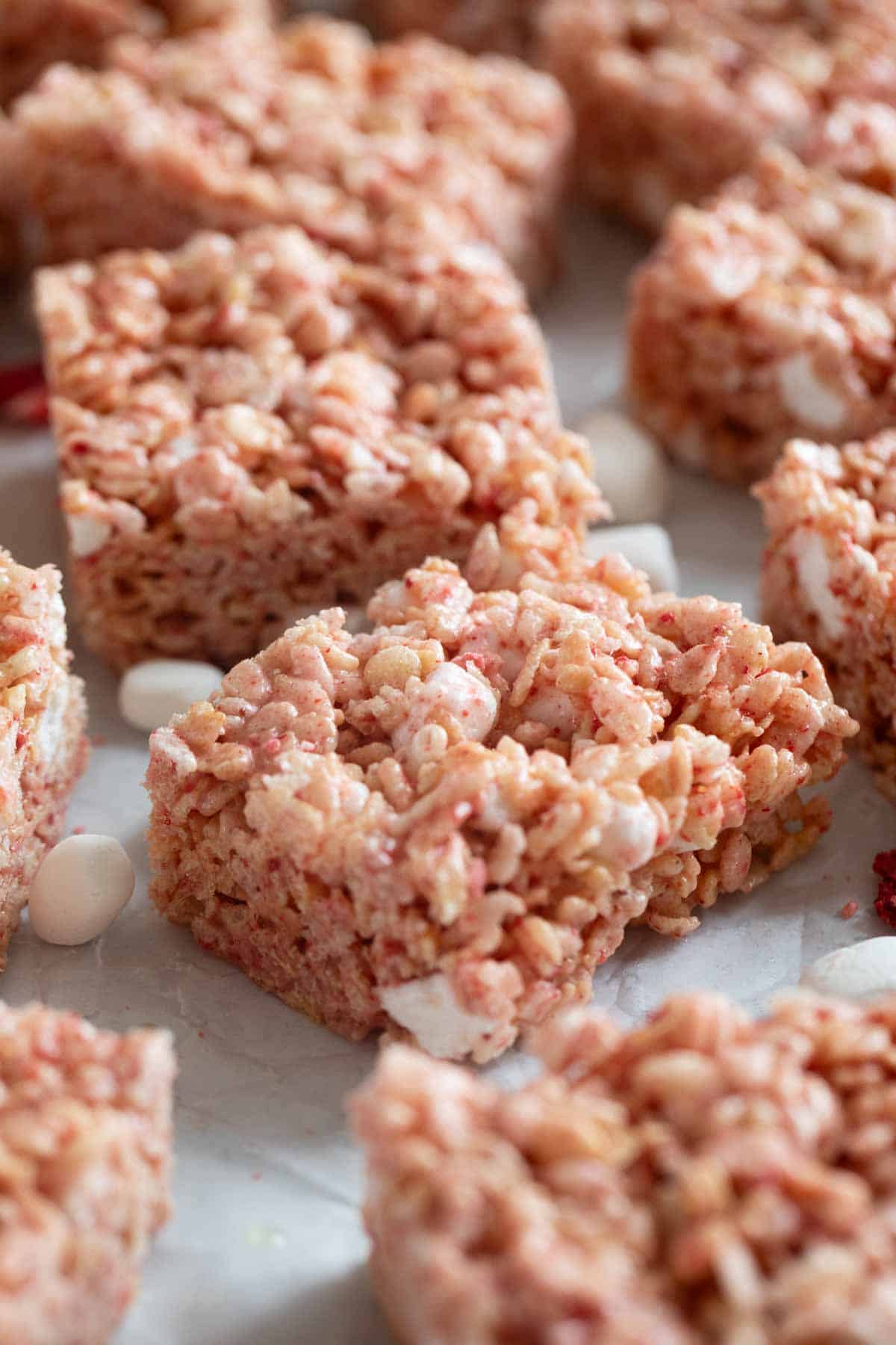 Strawberry Rice Krispie Treats cut into bars on parchment.