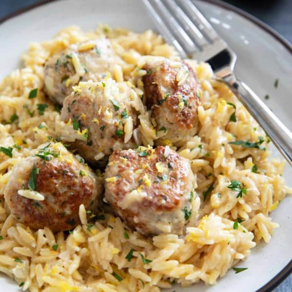 Plate filed with chicken meatballs on top of creamy lemon orzo.