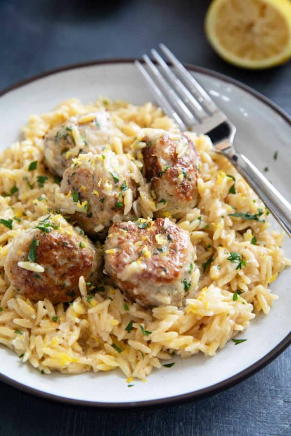 Plate filed with chicken meatballs on top of creamy lemon orzo.