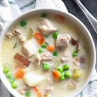 Bowl of chicken stew with chicken thighs, potatoes, and vegetables.