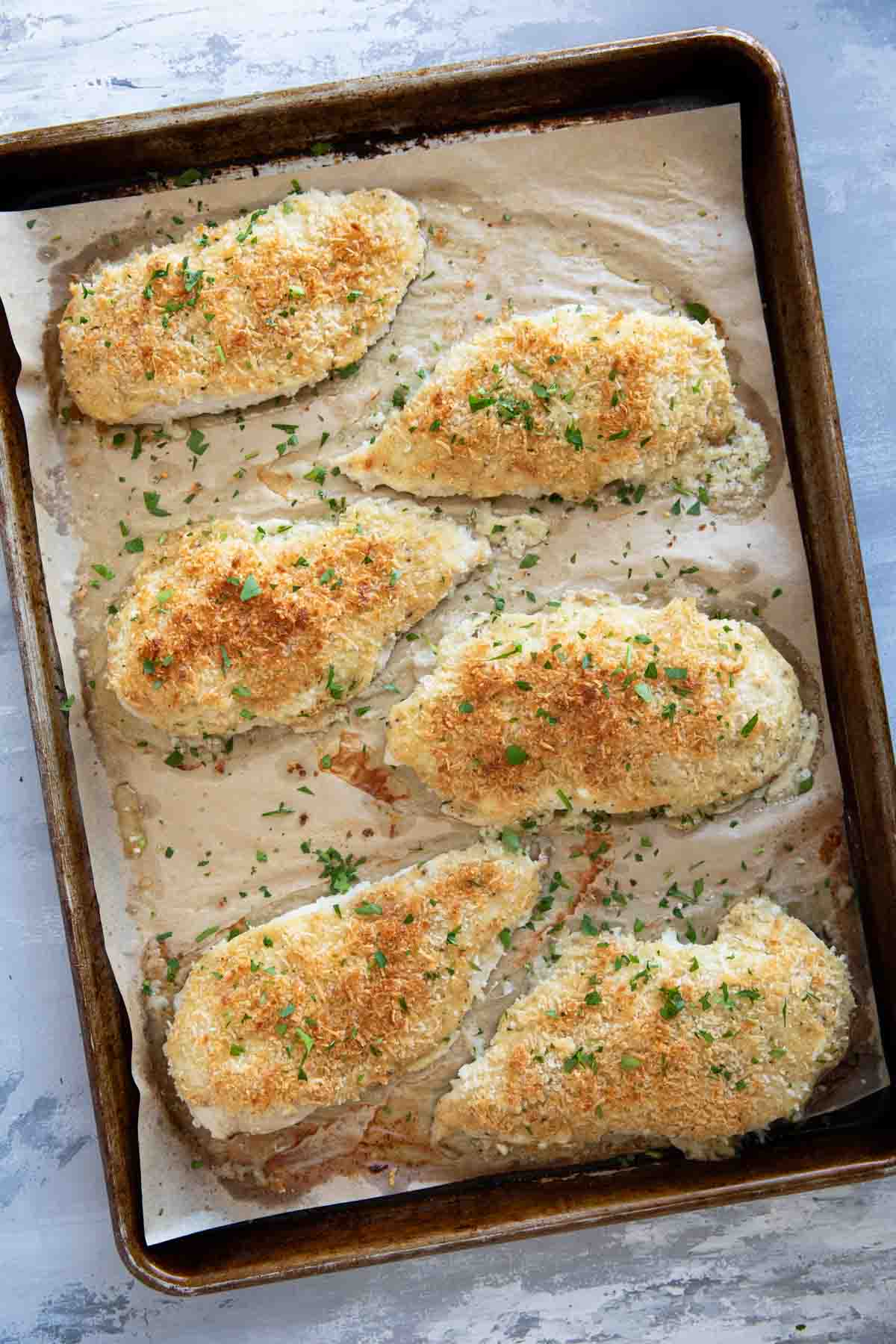 Baking sheet with crunchy mayo chicken on parchment paper.