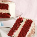 Slice of red velvet cheesecake cake with two layers of cake and one layer of cheesecake.