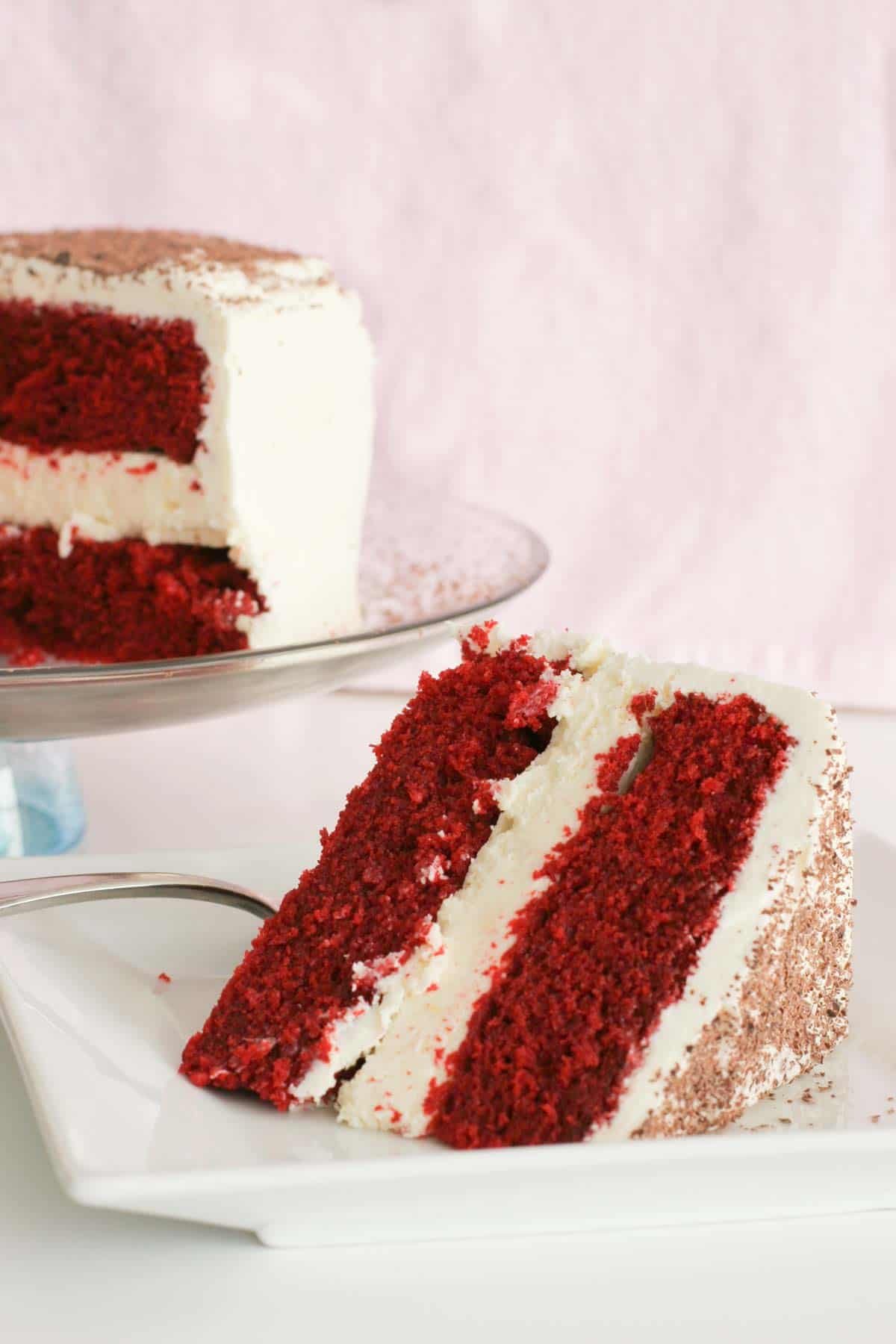 Slice of red velvet cheesecake cake with two layers of cake and one layer of cheesecake.