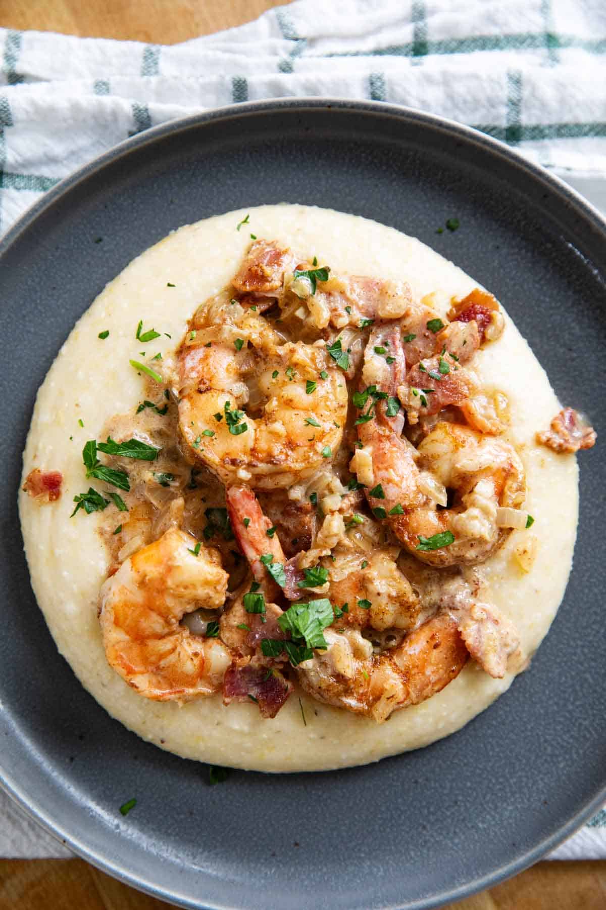 Gray plate with cheesy grits topped with shrimp.