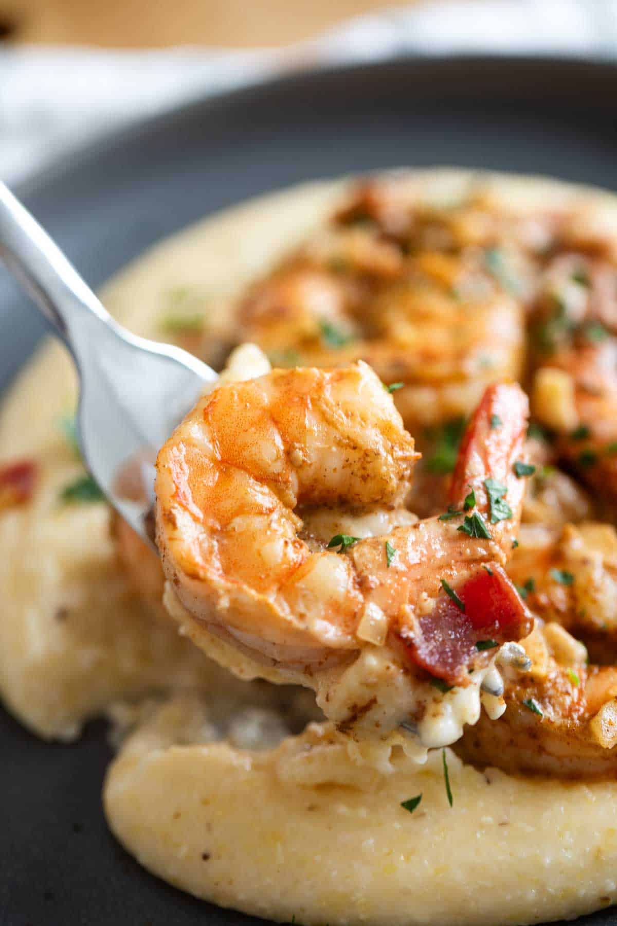 Fork with a bite of shrimp and grits on it.