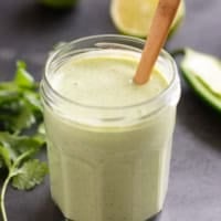 Tomatillo Ranch Dressing in a glass jar with a wooden spoon.