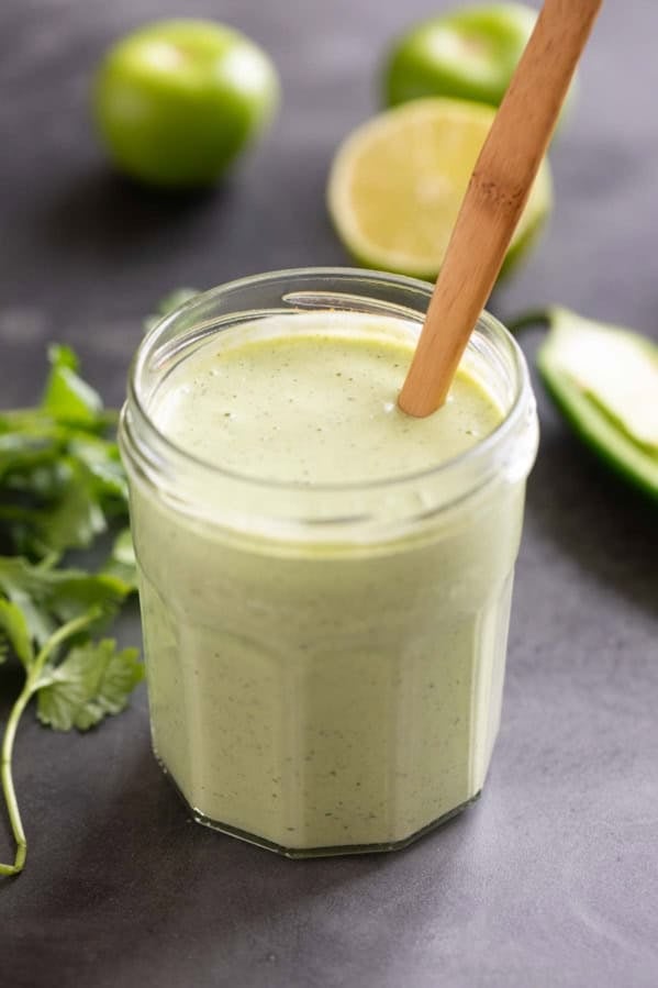 Tomatillo Ranch Dressing in a glass jar with a wooden spoon.