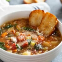 Bowl of Vegetable Soup with Orzo topped with parmesan cheese and toasted bread.