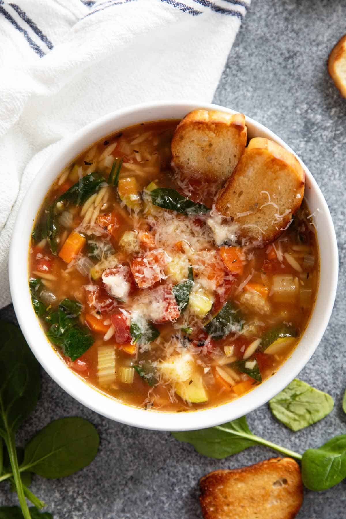 Bowl of Vegetable Soup with Orzo with toasted bread pieces.