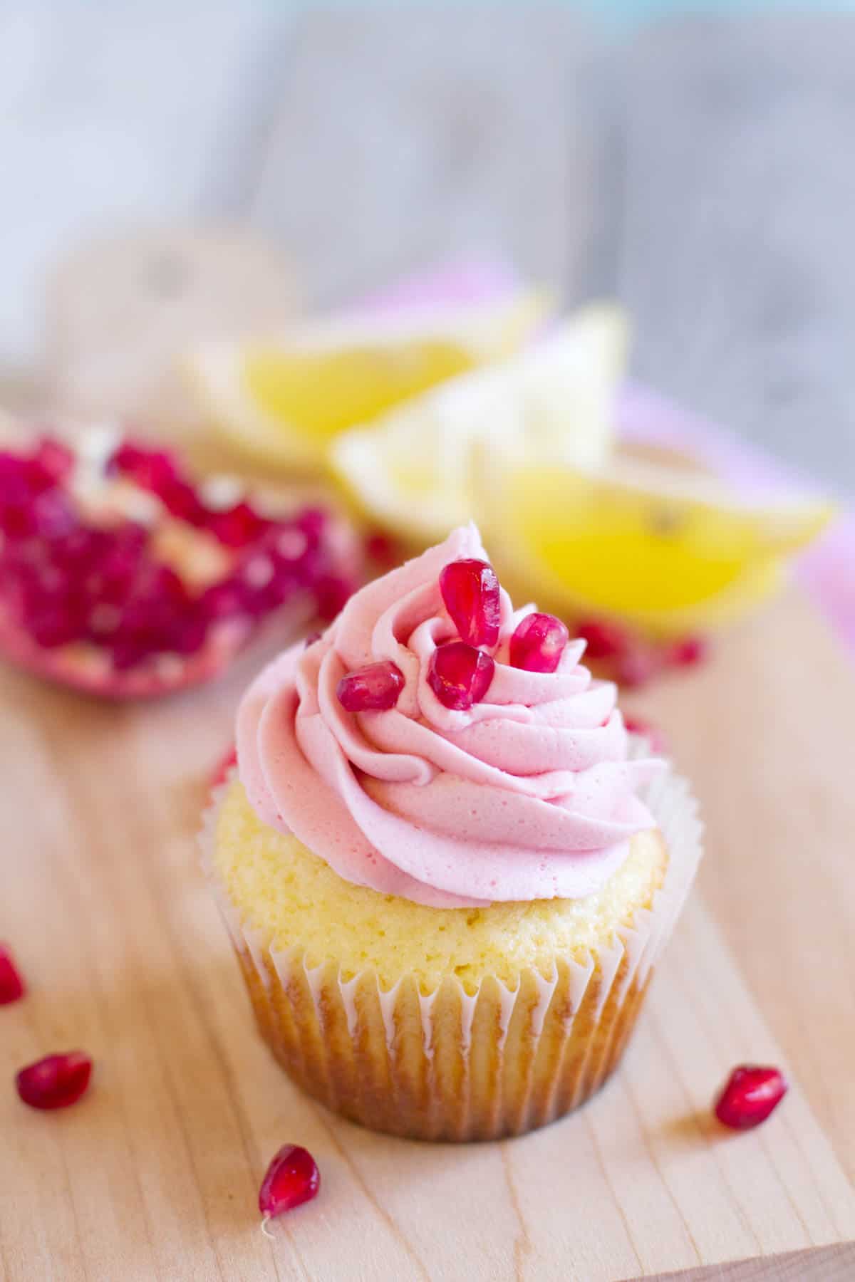 Lemon Pomegranate Cupcake with an open pomegranate behind.