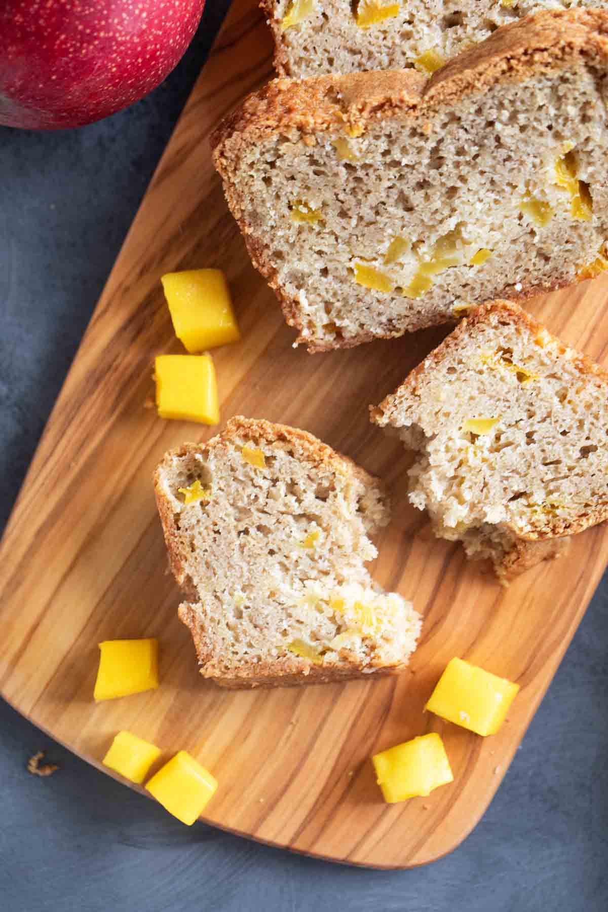 Sliced mango bread with one slice broken in half.