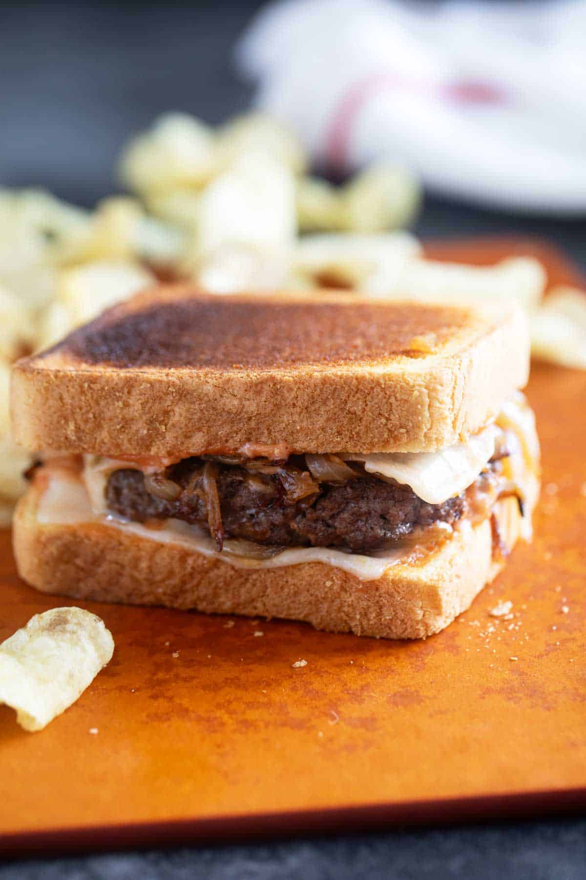 Patty Melt with special sauce and caramelized onions, served with potato chips.