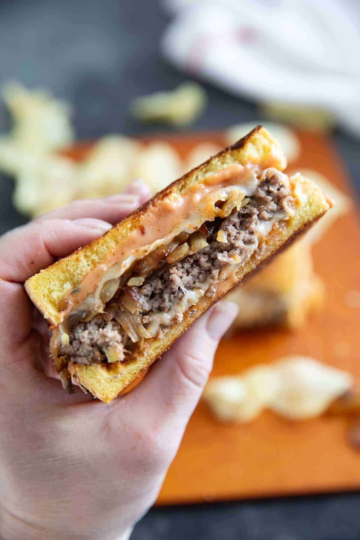 Hand holding half of a patty melt.