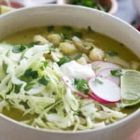 Bowl of Pozole Verde topped with shredded cabbage and radishes.