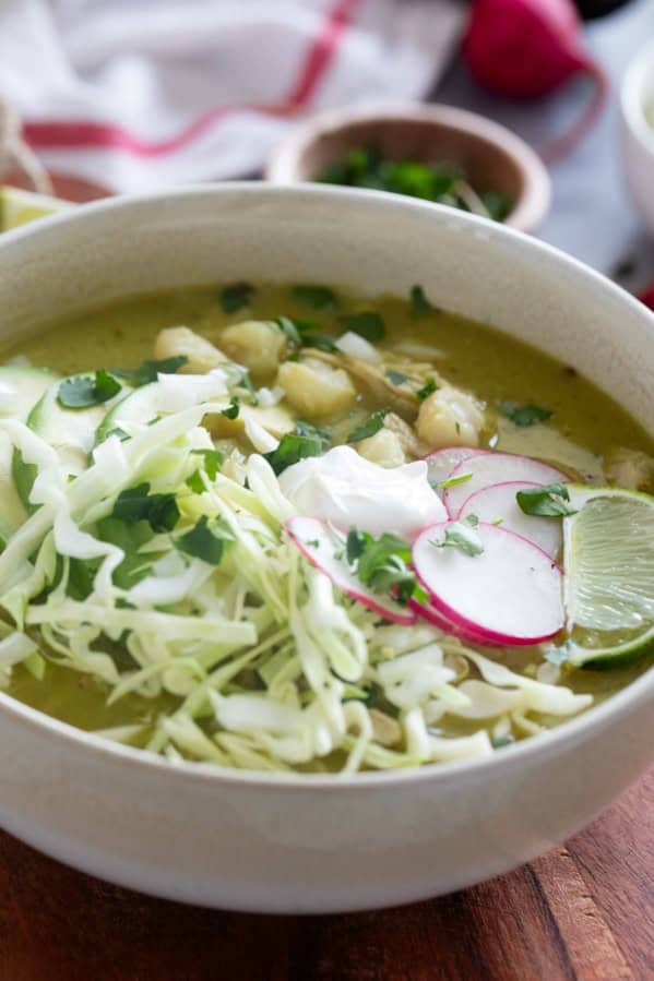 Bowl of Pozole Verde topped with shredded cabbage and radishes.