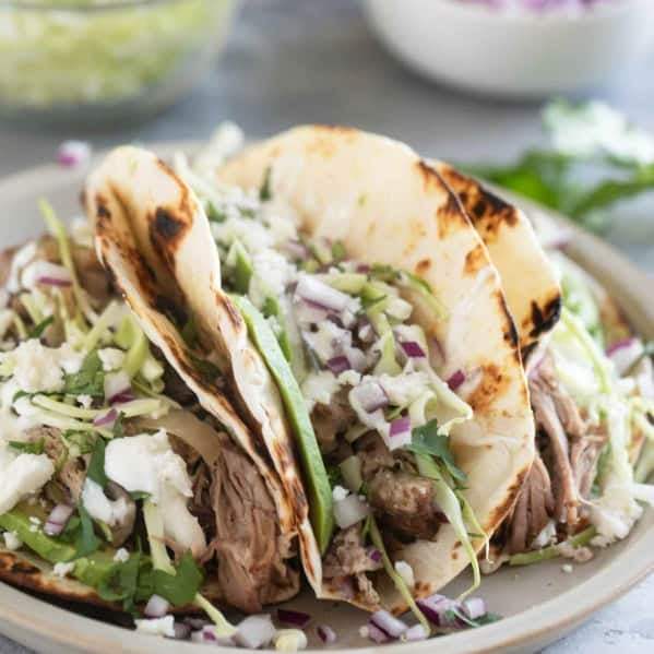 Shredded Pork Tacos topped with cabbage, onions, avocado, and more.