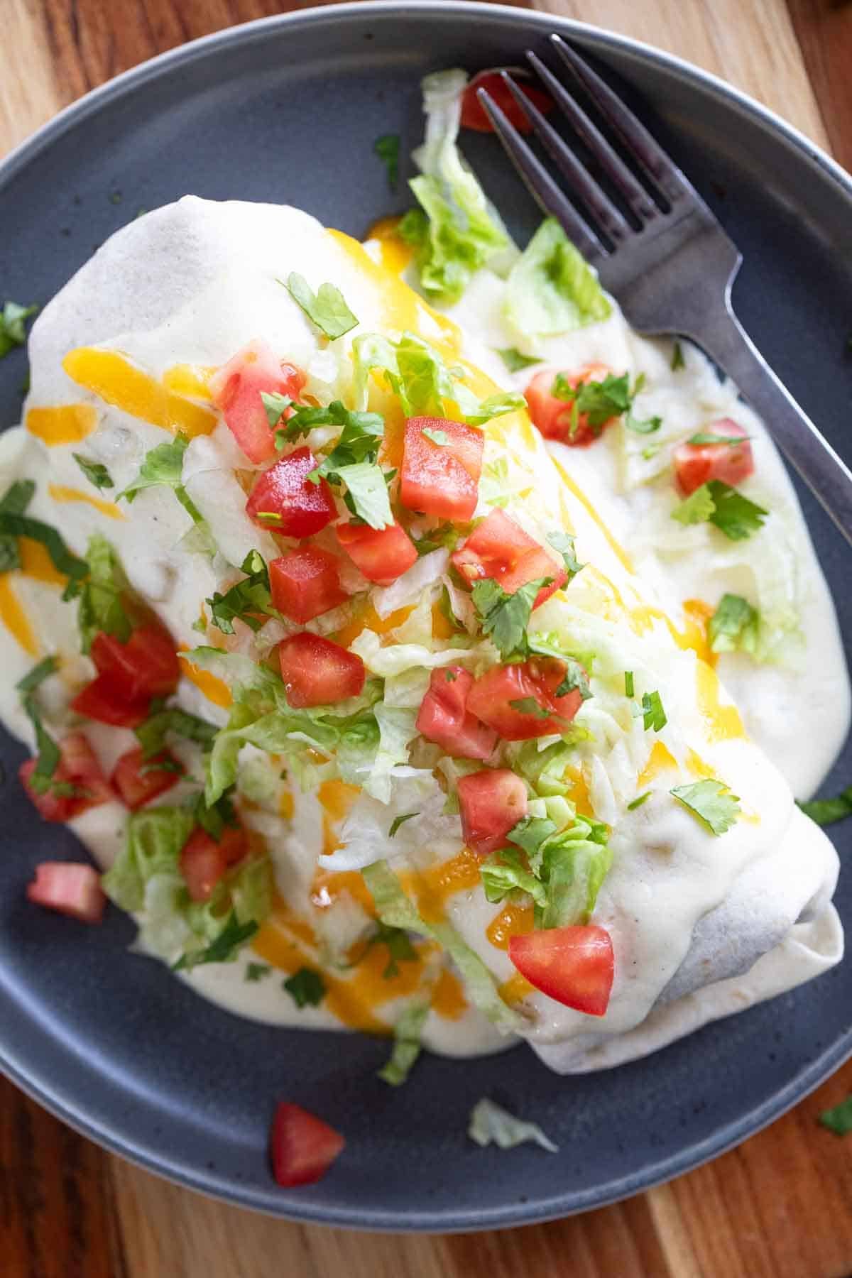 Smothered Burrito covered in green Chile sauce, cheese, tomatoes, and lettuce.