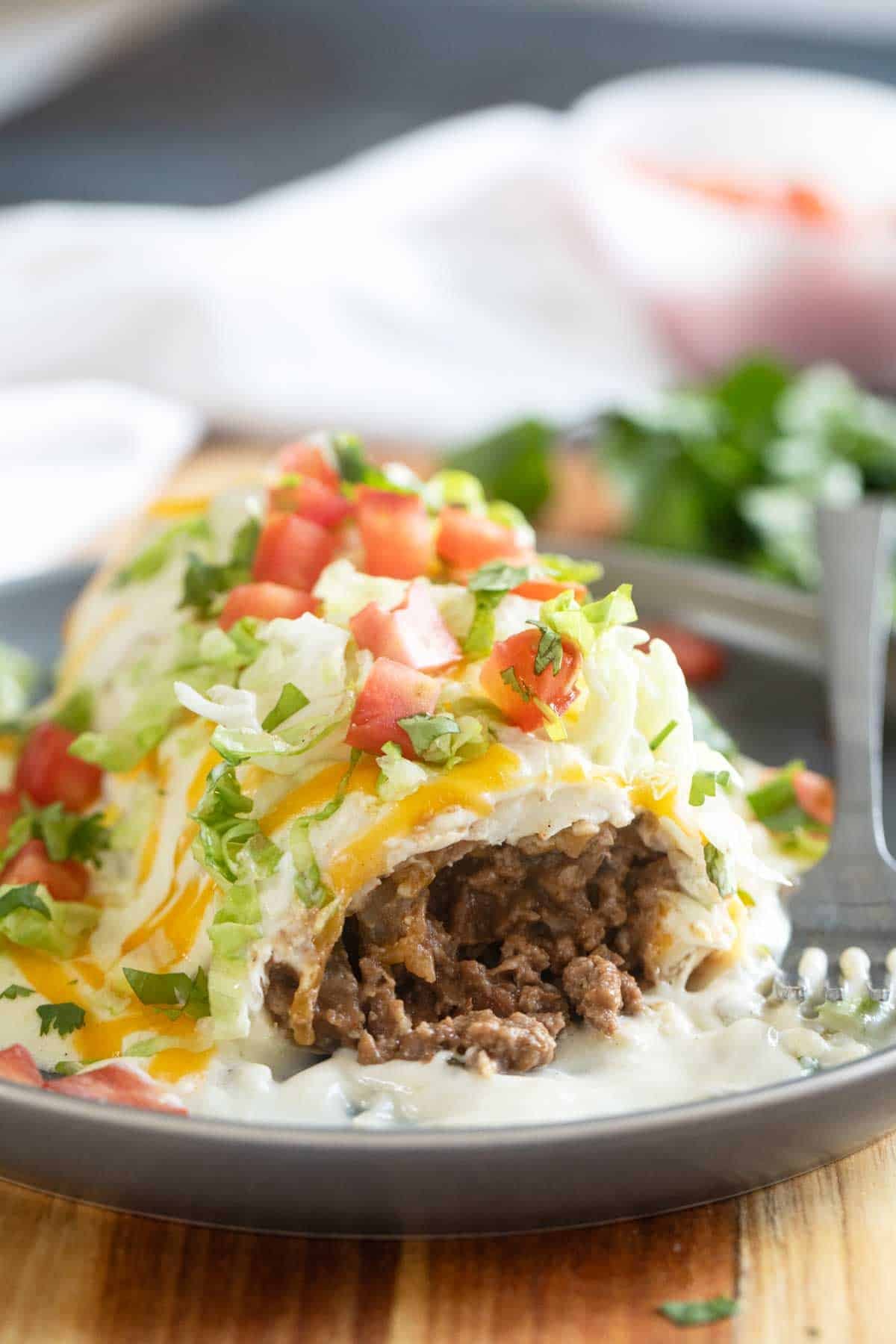 Smothered Burrito with Green Chile Sauce with a bite taken from it to show ground beef filling.