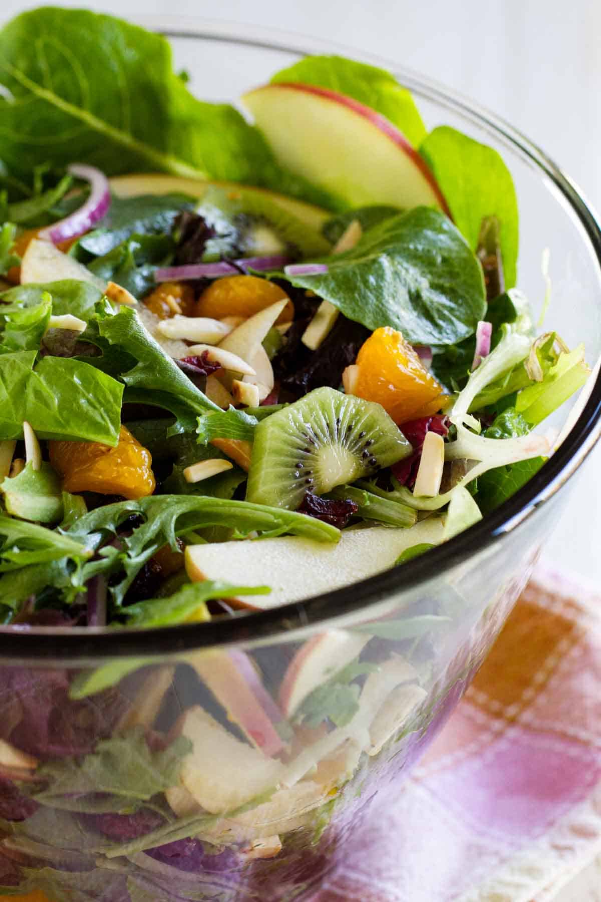 Glass bowl filled with Steph's Summer Salad with kiwi and oranges.